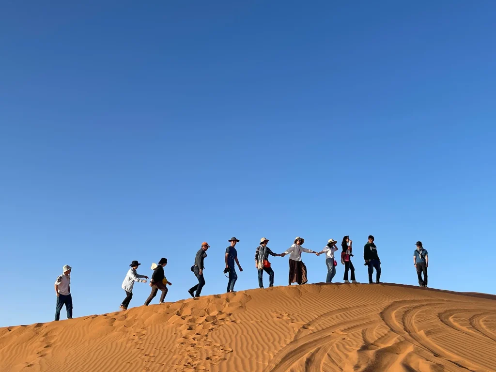 Group walking along a dune ridge at Erg Chebbi